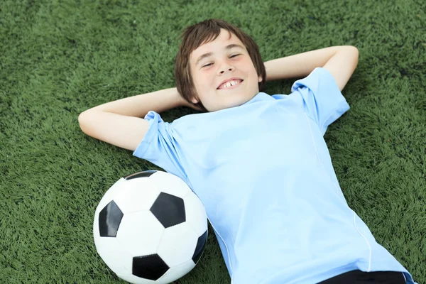 En ung fotbollsspelare med bollen på fältet — Stockfoto