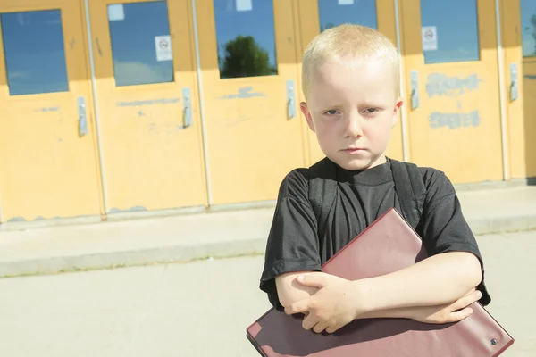 Een jongen op de speelplaats van zijn school met een backpak — Stockfoto