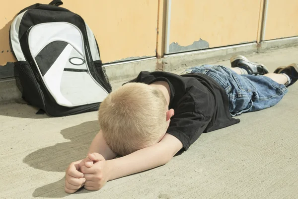 Un chico muy triste en el patio de la escuela —  Fotos de Stock