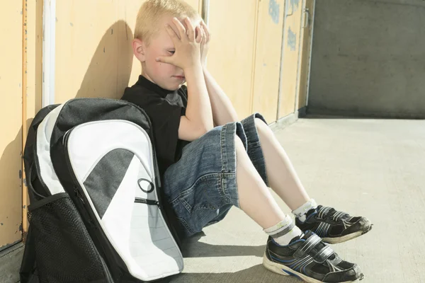 Очень грустный мальчик на школьной площадке — стоковое фото
