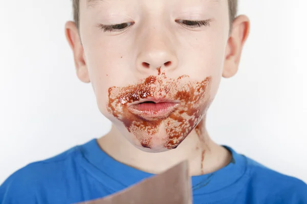 Jongen eten chocolade voor een witte achtergrond — Stockfoto