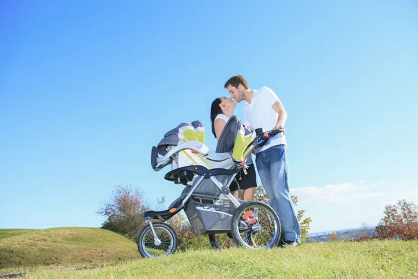 Una familia joven y feliz con un pequeño bebé al aire libre —  Fotos de Stock