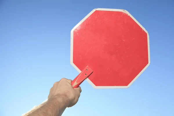 A hand holding a stop sign blue sky background. — Stock Photo, Image