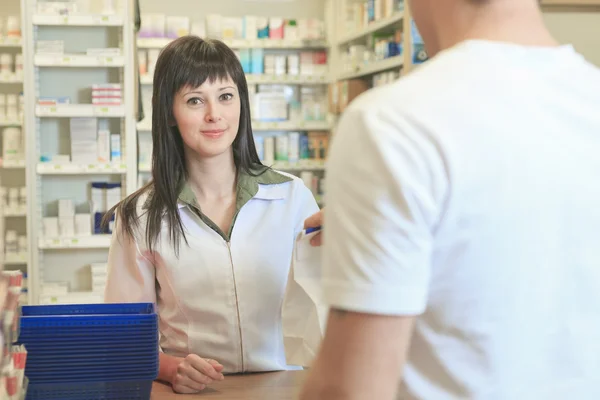 Um farmacêutico que ajuda o cliente no lugar contrário — Fotografia de Stock