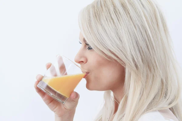 Leuke vrouw drinken sinaasappelsap op zoek naar de camera in de — Stockfoto