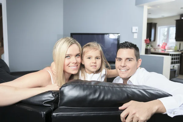 Uma família jovem assistindo TV juntos em casa — Fotografia de Stock