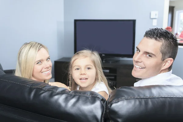 一个年轻的家庭，一起在家里看电视 — 图库照片