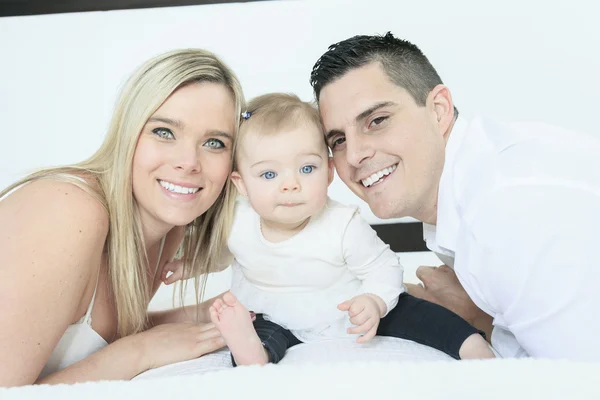 Una familia feliz en la cama blanca en el dormitorio —  Fotos de Stock