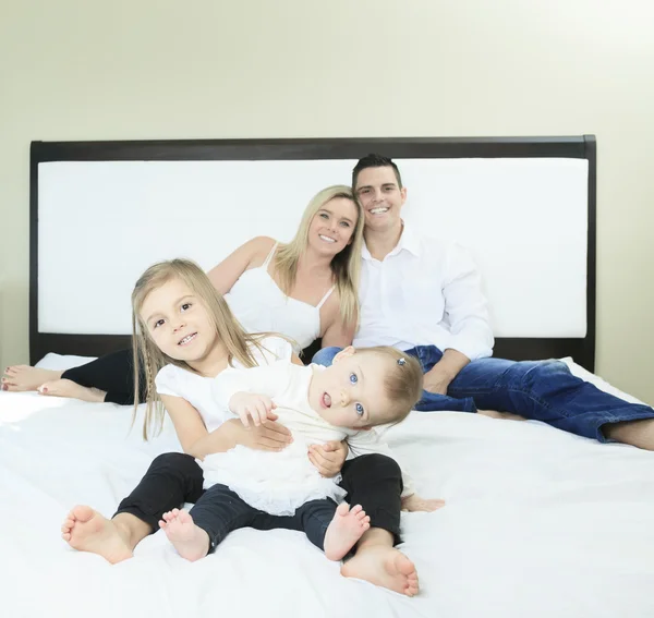 寝室の白いベッドの上の幸せな家族 — ストック写真