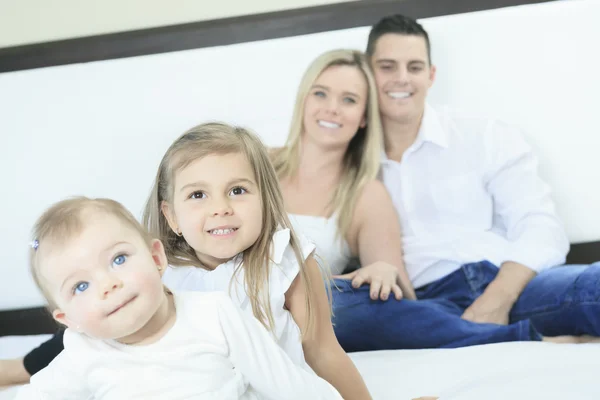 Una familia feliz en la cama blanca en el dormitorio —  Fotos de Stock