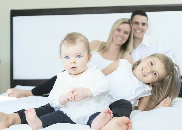 Een gelukkig gezin op wit bed in de slaapkamer — Stockfoto