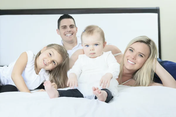 Een gelukkig gezin op wit bed in de slaapkamer — Stockfoto