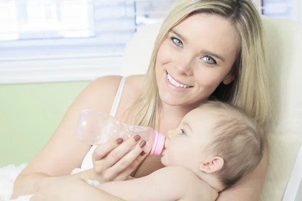 Young mother at home feeding their new baby girl with a milk bot — Stock Photo, Image