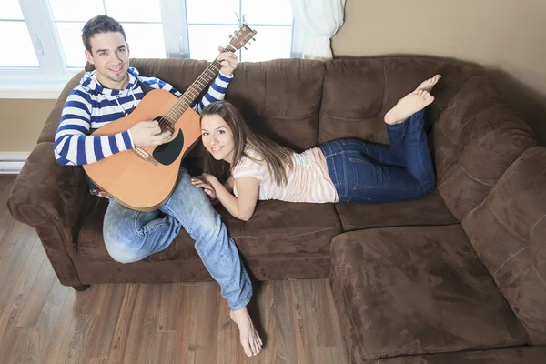 Een knappe man zijn vriendin met gitaar thuis in Serenade — Stockfoto