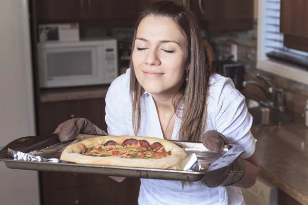 Kobieta z pyszną pizzę na kuchni — Zdjęcie stockowe