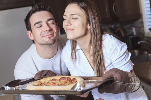 Una giovane coppia felice che mangia pizza in cucina — Foto Stock