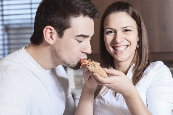 Un jeune couple heureux mangeant de la pizza à la cuisine — Photo