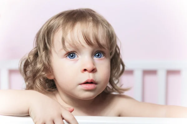 Un bébé dans son berceau avec un fond rose — Photo