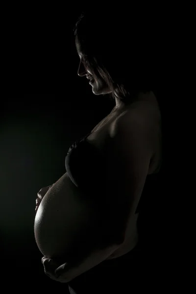 一名孕妇在黑色的背景上一个肚皮 — 图库照片