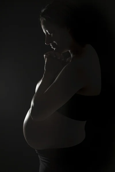 A belly of a pregnant woman on the black background — Stock Photo, Image