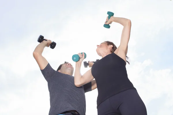 Una joven pareja caucásica haciendo ejercicio con pesas afuera — Foto de Stock
