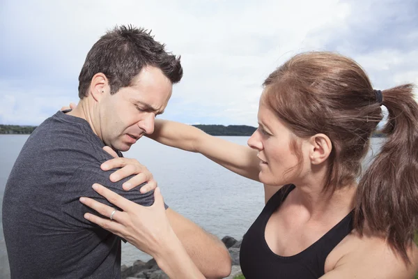 Kvinna hjälper att man med skadade axeln — Stockfoto