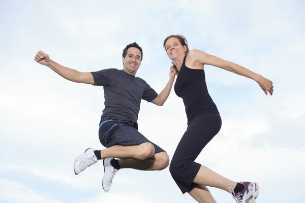 A young couple jumping on the meadow — Stock Photo, Image