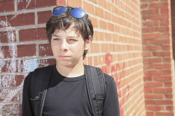 Un ritratto ragazzo adolescente con skateboard contro muro di mattoni con — Foto Stock