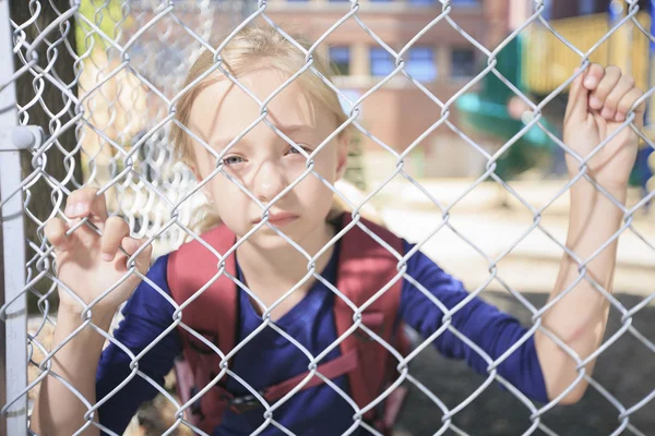 Una niña triste en el patio de recreo de la escuela — Foto de Stock