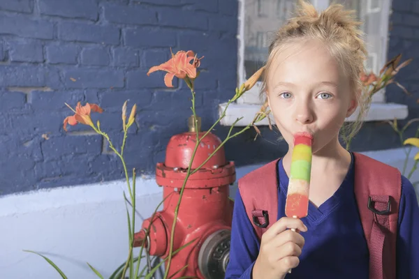 Een gelukkig meisje buiten met rugzak en lolly — Stockfoto