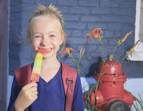 Een gelukkig meisje buiten met rugzak en lolly — Stockfoto