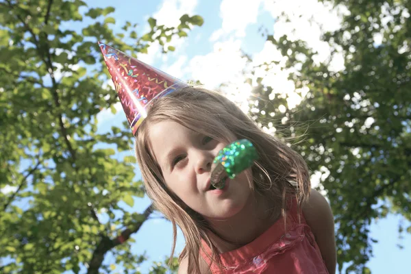 Dışarıda küçük bir kız doğum günü şapka ve trompet — Stok fotoğraf