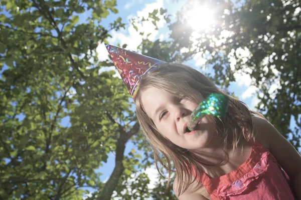 A little girl outside with birthday hat and trumpet — Stock Photo, Image