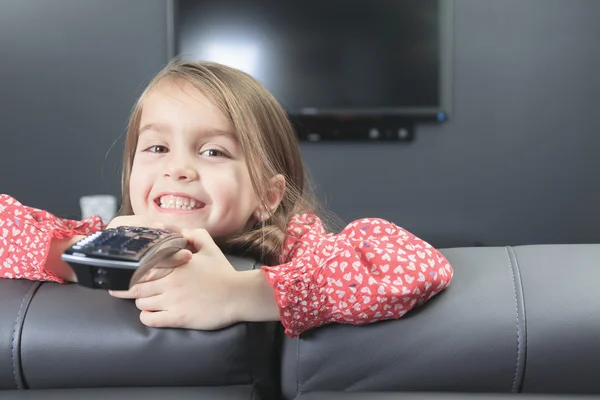 Uma menina bonita com controle remoto na frente da TV . — Fotografia de Stock