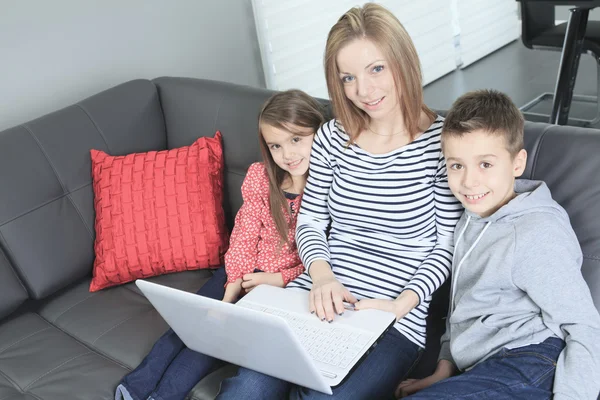 Imagen de una familia amigable sentada en el sofá y mirando a lapt —  Fotos de Stock