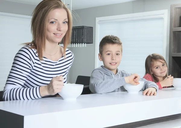 Famille souriant à la caméra au petit déjeuner dans la cuisine — Photo