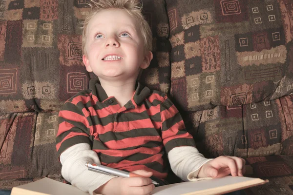 Un niño con un libro en el sofá — Foto de Stock