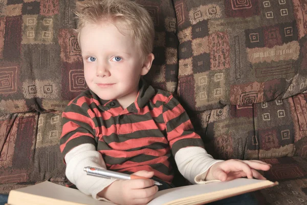 Un niño con un libro en el sofá —  Fotos de Stock
