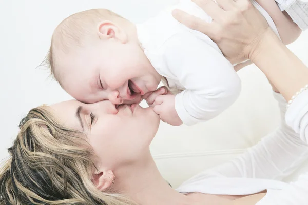 Madre cariñosa besando a su bebé aislado sobre fondo blanco — Foto de Stock