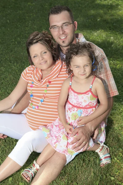 Glada leende familj sitter på gräset — Stockfoto