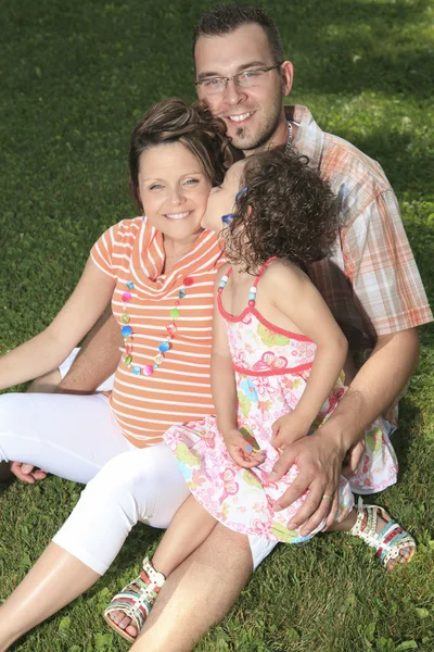 Feliz família sorridente sentada na grama — Fotografia de Stock