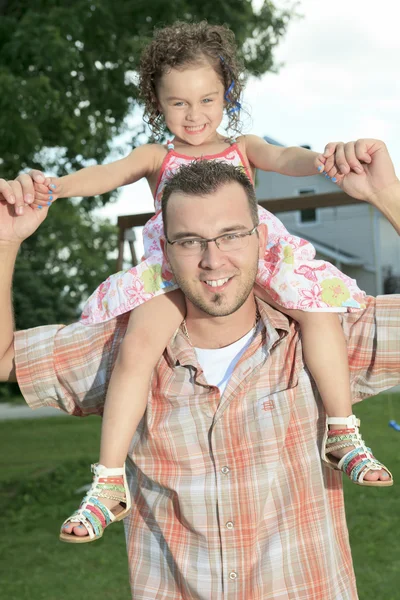 Pai e filhote. Jovem segurando uma menina nos ombros — Fotografia de Stock