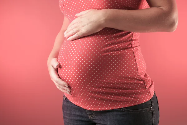 Una hermosa mujer embarazada sobre fondo rojo —  Fotos de Stock