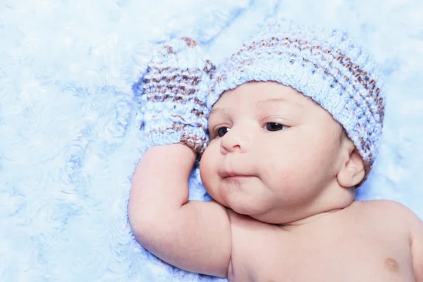 A Closeup of the face of a tiny, newborn baby boy wearing a blue — Stock Photo, Image