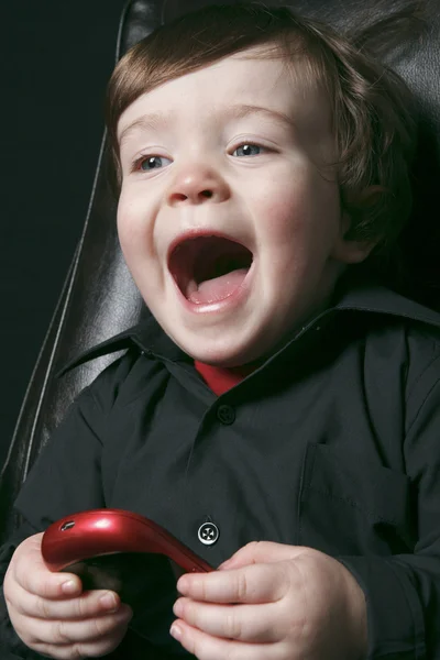 Een jongen zit in een stoel van het Bureau geïsoleerd op zwarte achtergrond — Stockfoto