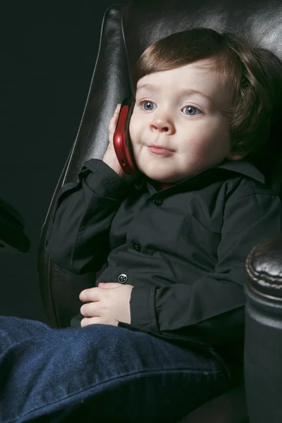 Een jongen zit in een stoel van het Bureau geïsoleerd op zwarte achtergrond — Stockfoto