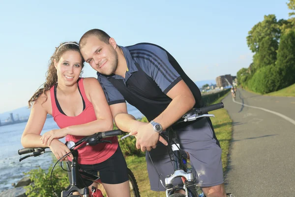 Portrait of a happy young couple on mountain bikes — Stock Photo, Image