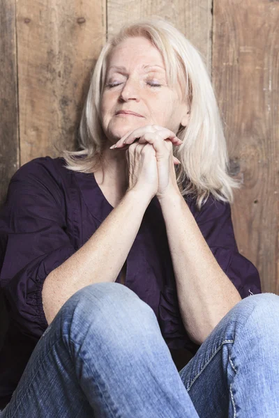 Een ouderdomsdeken bidden met een houten achtergrond — Stockfoto