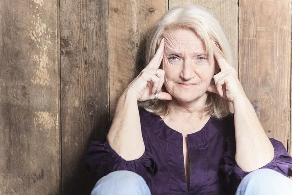 Une femme âgée prie avec un fond de bois — Photo