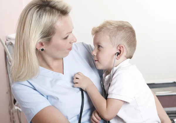 Médico femenino usando estetoscopio para examinar a un niño dulce —  Fotos de Stock